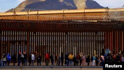 Migrantes hacen cola cerca de la valla fronteriza, después de cruzar el río Bravo, para solicitar asilo en El Paso, Texas, visto desde Ciudad Juárez, México, el 5 de enero de 2023.