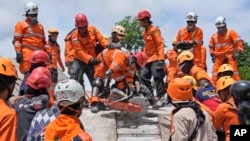Los rescatistas usan una sierra mientras intentan recuperar el cuerpo de una víctima del terremoto de debajo de los escombros de un edificio derrumbado en Cianjur, Java Occidental, Indonesia, el 22 de noviembre de 2022.