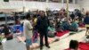 Gustavo Banda (de pie a la derecha), pastor del Templo Embajadores de Jesús, en el albergue para migrantes más grande de Tijuana, México, habla con algunos de ellos el lugar, el 13 de octubre de 2022.