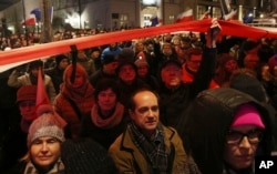 Polish people protest plans by the ruling populist party for laws that would give it greater control over the courts and the national election commission, in Warsaw, Poland, Nov. 24, 2017.