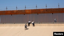Los migrantes que buscan asilo salen del río Bravo después de cruzarlo para entregarse a los agentes de la Patrulla Fronteriza de los EEUU para solicitar asilo en El Paso, Texas, EEUU, visto desde Ciudad Juárez, México, el 13 de abril de 2022. 