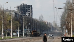 Un residente local cruza una calle dañada durante el conflicto entre Ucrania y Rusia en la ciudad portuaria sureña de Mariúpol, Ucrania, el 15 de abril de 2022. 