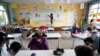 A teacher, wearing a protective face mask, teaches to schoolchildren in a classroom at a private school during its reopening in Saint-Sebastien-sur-Loire near Nantes.