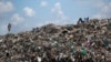 FILE - A man who scavenges for a living takes a rest next to a Marabou stork on top of a mountain of garbage at the dump in the Dandora slum of Nairobi, Kenya, Nov. 12, 2015.
