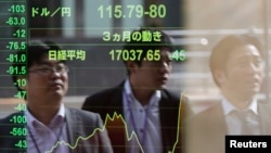 Passers-by are reflected on an electronic board showing Japan's Nikkei stock average and the Japanese yen's exchange rate against the U.S. dollar (top) at a brokerage in Tokyo, November 17, 2014.
