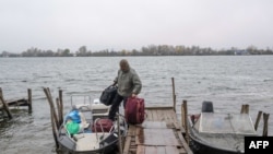 Un hombre sale de su casa hacia su residencia de verano en una isla en el río Dnipro después de un ataque a una reserva de petróleo en Kherson el 20 de noviembre de 2022, en medio de la invasión rusa de Ucrania.