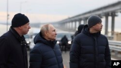 El presidente ruso, Vladimir Putin, en el centro, y el viceprimer ministro Marat Khusnullin, a la izquierda, visitan el puente de Crimea que conecta la parte continental de Rusia y la península de Crimea sobre el estrecho de Kerch, que resultó dañado por un atentado con camión bomba en octubre, después de las obras de restauración, no lejos de Kerch , Crimea, lunes 5 de diciembre de 2022.