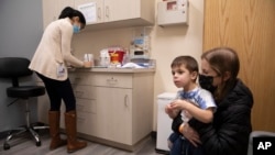 Una mujer y su hijo de 3 años duratnte una cita para una dosis de la vacuna de Moderna contra el COVID-19 en un ensayo en Commack, Nueva York el 30 de noviembre de 2021.
