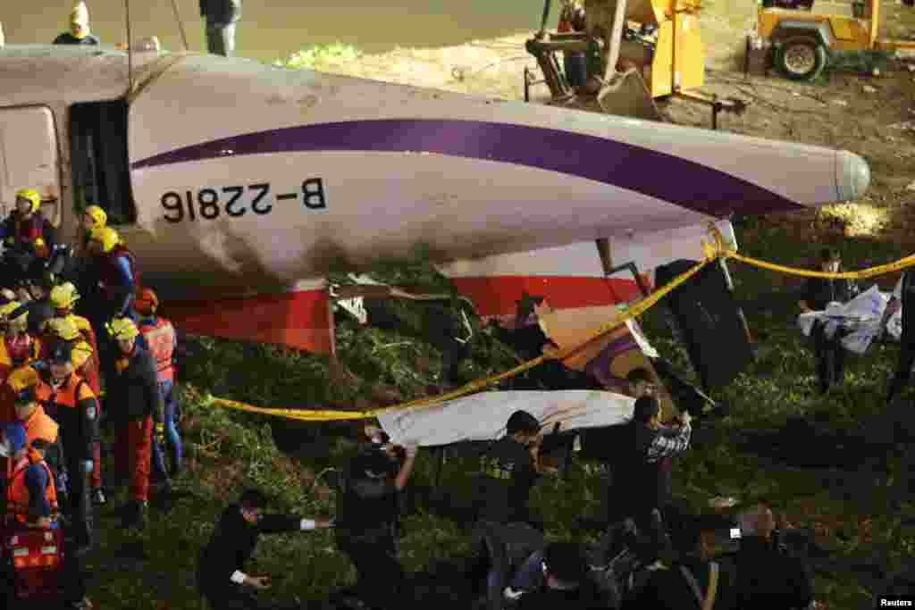 Rescuers carry one body in a bag away after a TransAsia Airways plane crash landed in a river, in New Taipei City.