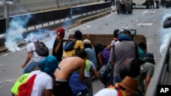 Los manifestantes lanzan piedras contra oficiales de la Policía Nacional Bolivariana durante una protesta en Caracas, Venezuela, el sábado 8 de abril de 2017.
