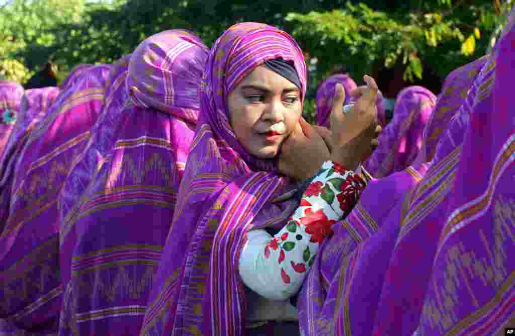 Seorang perempuan merapikan kerudungnya pada parade budaya dan lingkungan di Bali, Indonesia.