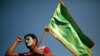 FILE - A supporter of Shiite rebels, known as Houthis, holds a green flag with Arabic writing reading, 'At your order, oh messenger of Allah,' during a celebration of Muhammad's birth in Sanaa, Yemen, in October 2020.