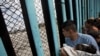 FILE - A member of the Central American migrant caravan, holding a child, looks through the border wall toward a group of people gathered on the U.S. side, as he stands on the beach where the border wall ends in the ocean, in Tijuana, Mexico, April 29, 2018. 