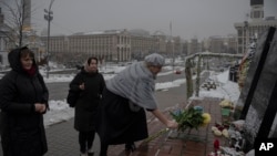 La gente deposita flores en un monumento dedicado a las personas que murieron en enfrentamientos con las fuerzas de seguridad, en la Plaza Independiente (Maidan) en Kiev, Ucrania, el lunes 21 de noviembre de 2022.