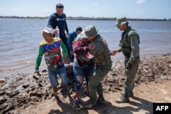La gente llega a la costa de Puerto Guacara en La Paragua, estado Bolívar, Venezuela, el 23 de febrero de 2024, después del colapso de una remota mina ilegal. (Foto de Ronald PEÑA/AFP)