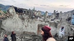En esta foto publicada por la agencia de noticias estatal Bakhtar, los afganos observan la destrucción causada por un terremoto en la provincia de Paktika, este de Afganistán, el 22 de junio de 2022.