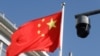 ARCHIVO - Una cámara de seguridad vista frente a una bandera china que ondea en una calle de Beijing, China, en noviembre de 2021.