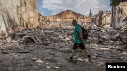 ARCHIVO - Un residente local camina frente a un edificio destruido por un ataque militar, en Lysychansk, región de Luhansk, Ucrania, el 17 de junio de 2022.