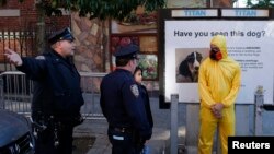 Policías de Nueva York le piden a un hombre en disfraz de Halloween imitando el equipo protector contra el ébola que se aleje del lugar donde vive el Dr. Craig Spencer que ha dado positivo al virus.
