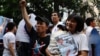 FILE - Tran Thi Nga, right, holds her son and an anti-China poster as she takes part in a rally in Hanoi, July 8, 2012.