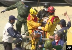 In this image made from video, Lee Tsung-tien, 42, is attended to by rescue workers after he was pulled out conscious from a building which collapsed after an earthquake in Tainan, Taiwan, Feb. 8, 2016.