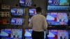 A salesman watches Prime Minister Narendra Modi addressing to the nation, on TV screens inside a showroom in Mumbai, India, March 27, 2019. 