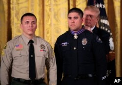El presidente Donald Trump coloca la Medalla al Valor al oficial de policía Nicholas Koahou, de Redlands, California, durante una ceremonia en el Salón Oriental de la Casa Blanca, a la izquierda el Cabo Rafael Ixco del Departamento del Alguacil del Condado de San Bernardino, California, que también recibió el honor. Martes 20 de febrero de 2018.