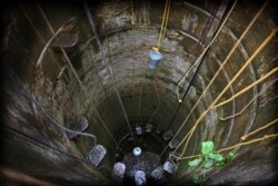 In this July 16, 2019, photo, Indians fetch water from almost a dried well on the outskirts of Chennai in Southern Indian state of Tamil Nadu.