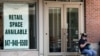 A woman looks at her phone outside of a rental sign displayed at a store in Deerfield, Ill., June 11, 2020.