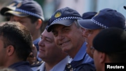 El presidente de Brasil, Jair Bolsonaro, posa con oficiales de policía en la favela Estrutural, en Brasilia, el 27 de abril de 2019.