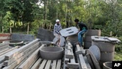 FILE - In this May 30, 2016 photo, Bangladeshi volunteers, working to spread awareness on sanitation, lift toilet seats in Bormi village, near Dhaka, Bangladesh.