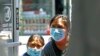Two women peer into a clothing store to see if it is open, June 8, 2020, in the Sunset Park neighborhood of the Brooklyn borough of New York. 