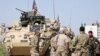 FILE - Kurdish fighters from the People's Protection Units (YPG) chat with members of U.S. forces in the town of Darbasiya next to the Turkish border, Syria.