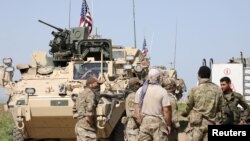 FILE - Kurdish fighters from the People's Protection Units (YPG) chat with members of U.S. forces in the town of Darbasiya next to the Turkish border, Syria.