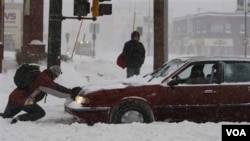 Lucha desigual, un buen samaritano trata de ayudar a una mujer a desatascar su auto de la nieve en Saint Paul, Minnesota.