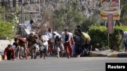 Yemenitas buscan refugio durante un tiroteo en una base militar en el puerto de Adén, en Yemen.