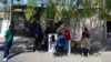 Migrantes venezolanos se cortan el pelo junto a las vías del tren bordeadas por tiendas de campaña improvisadas en la Ciudad de México, el martes 26 de marzo de 2024. 