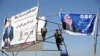 Afghan men installs election posters of parliamentarian candidates during the elections campaign for the upcoming election in Kabul, Afghanistan, Oct. 9, 2018.
