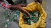 FILE - A worker gathers handfuls of cellphone printed circuit boards from a pile to put in a sack for recycling at a recycling facility near Nairobi, Kenya, in this Aug. 18, 2014 photo.