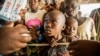 FILE - Refugees from the Democratic Republic of Congo look on during the distribution of biscuits in Sebagoro, Uganda, on Feb. 15, 2018.