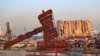 A justice symbol monument is seen in front of towering grain silos that were gutted in the massive Aug. 2020 explosion at the port that claimed the lives of more than 200 people, in Beirut, Lebanon, Aug. 4, 2021. 