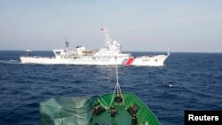 2014年5月14日, 在越南海岸外大约210公里海域，从越南巡逻船上看到的中国海警船。越南船只靠近中国在有争议水域部署的一座石油钻井平台时，会遭到中国船只抵近拦阻。