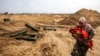 Seorang warga Palestina menggendong bayi berjalan melewati kontainer amunisi yang ditinggalkan oleh pasukan Israel saat dia melarikan diri lebih jauh ke selatan dari Khan Yunis di Jalur Gaza selatan, 2 Februari 2024. (Mahmud Hams / AFP)
