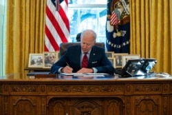 FILE - President Joe Biden signs a series of executive orders, in the Oval Office of the White House, in Washington, Jan. 28, 2021.