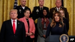 President Donald Trump listens as first lady Melania Trump speaks during an event on the opioid crisis, in the East Room of the White House, Oct. 24, 2018, in Washington.
