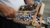 Government worker slashes counterfeit Louis Vuitton handbag during ceremonial destruction of fakes goods seized in raids, Manila, Philippines, June 30, 2011.