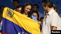 María Corina Machado, inminente ganadora de la primaria presidencial opositora, sostiene una bandera de Venezuela en su comando de campaña, amaneciendo este lunes 23 de octubre de 2023.