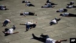 Activistas españoles acostados en el piso de una plaza en Madrid protestan en el Día Mundial de los Refugiados. Junio 19 de 2018.