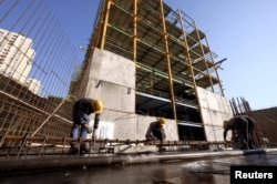 ARCHIVO-Obreros trabajan en un sitio de construcción en Teherán, Irán, el 20 de enero de 2016. El presidente iraní, Hassan Rouhani, dijo el 8 de mayo de 2018 que Estados Unidos no podría perjudicar a la economía iraní volviendo a imponer sanciones relacionadas con la energía nuclear.