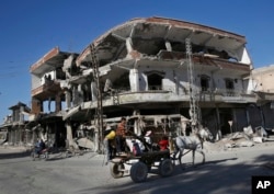 FILE - The remains of buildings line a street that was damaged the previous summer during fighting between U.S.-backed Syrian Democratic Forces fighters and Islamic State militants, in Raqqa, Syria, April 5, 2018.